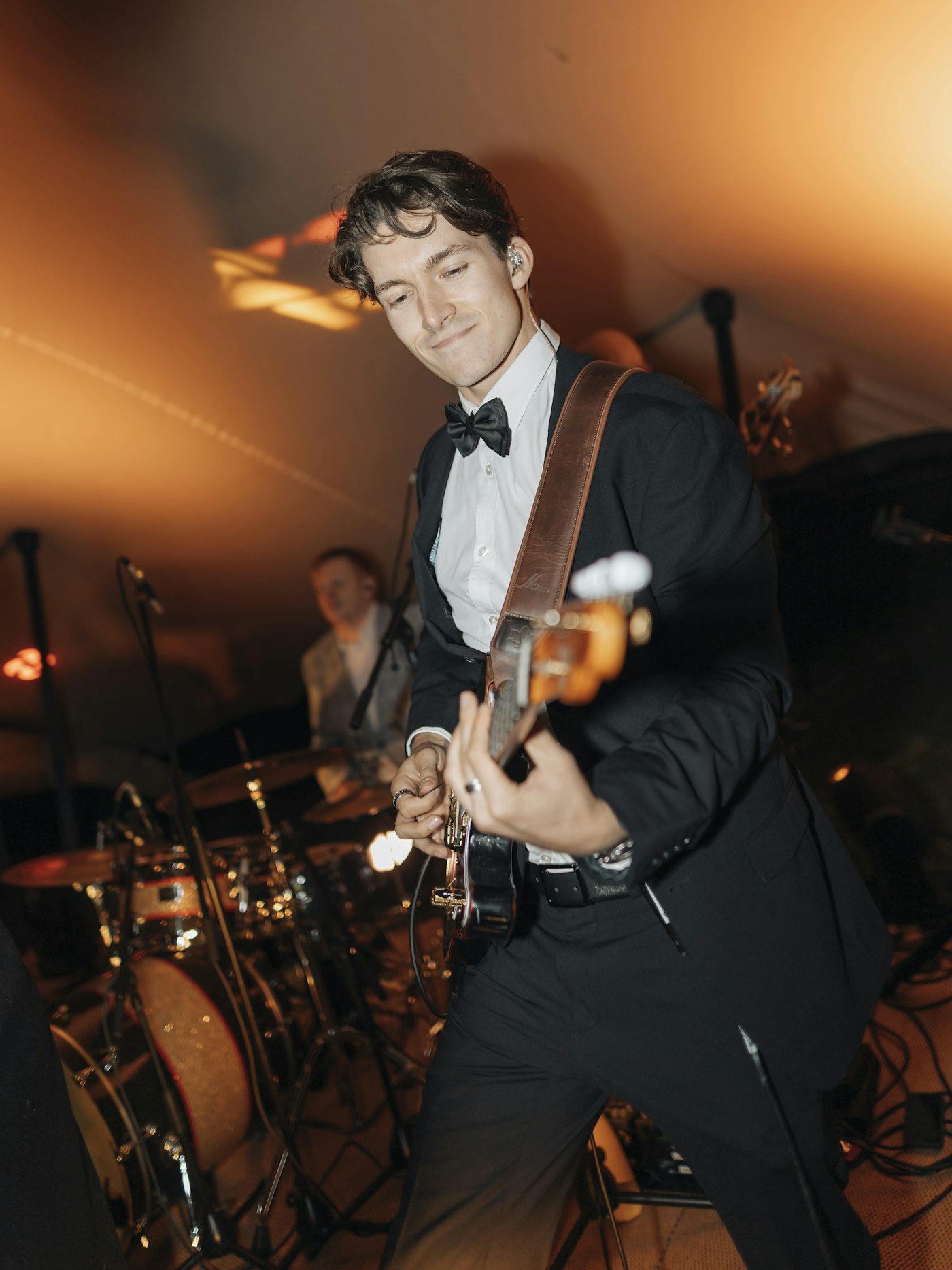Guitarist in a tuxedo and drummer playing at a wedding reception